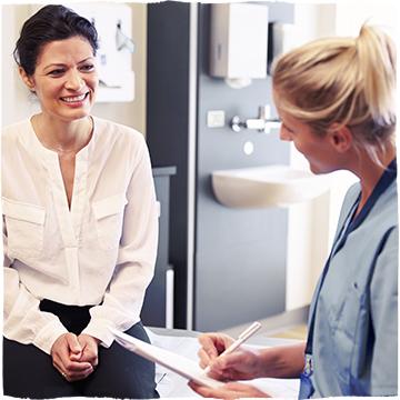 Female Physician, dressed in blue uniform is talking to her female patient.