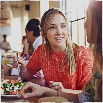 Women smiling while eating her meal.