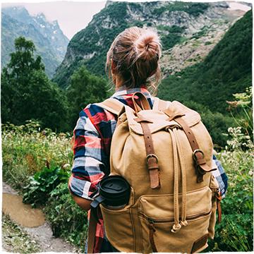 Woman walking a mountain valley, with her backpack.